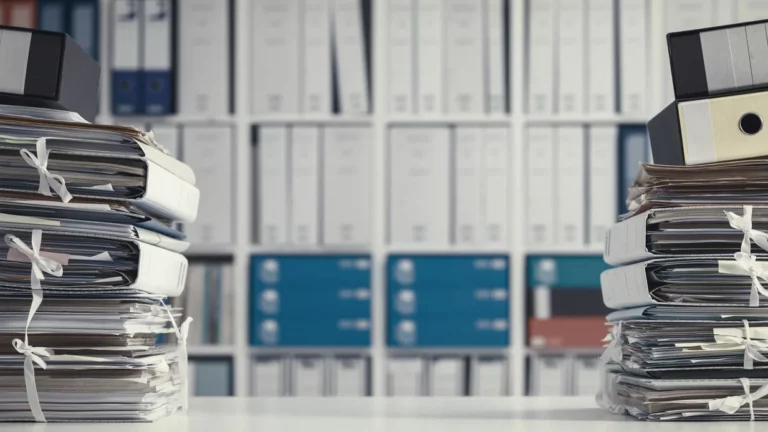 Stacks of paper documents and binders on a desk